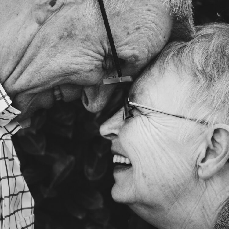 an elderly couple both wearing new affordable dentures and smiling at one another