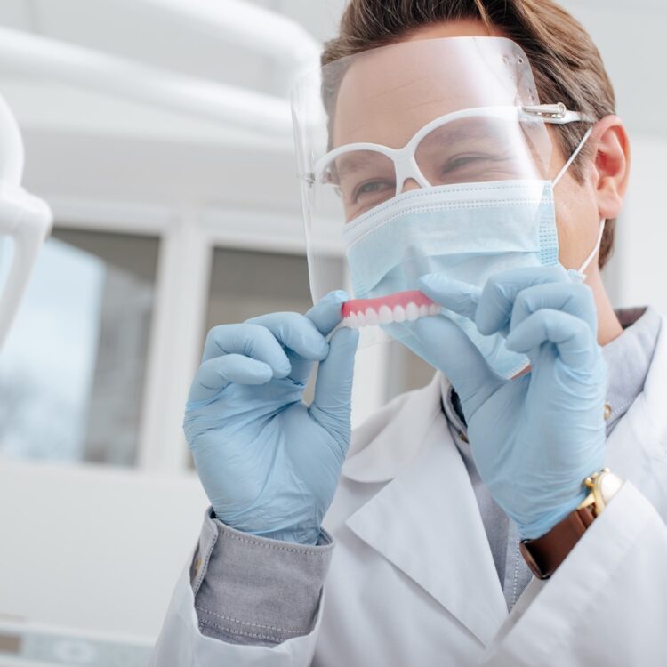 a dentist delivering a set of affordable dentures to a happy patient