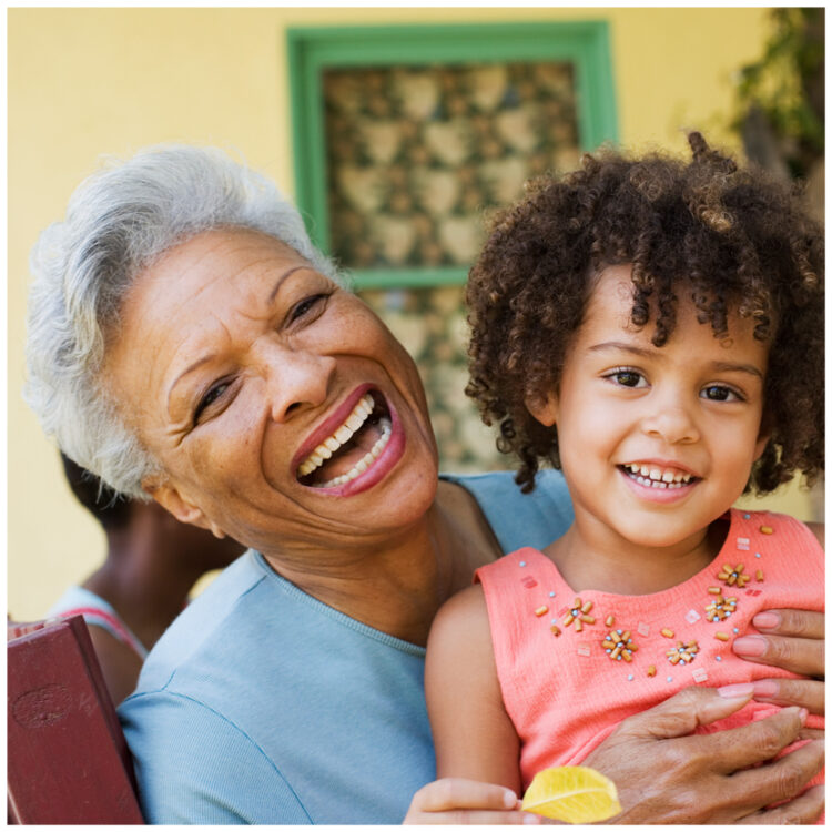 a Medicaid patient wearing affordable dentures and smiling with her granddaughter